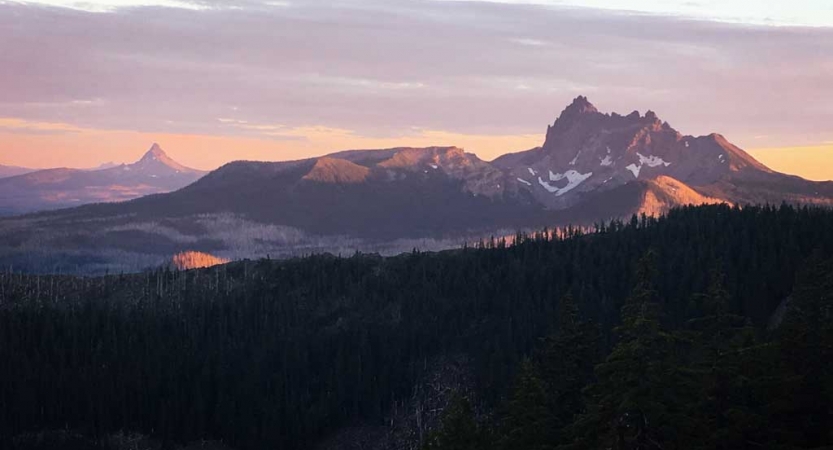 a vast mountainous landscape appears purple and pink from the sunrise or sunset